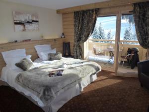 een slaapkamer met een groot bed en een balkon bij Hôtel Restaurant "Les Sapins" Wellness & Gourmet in Manigod
