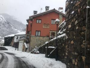 a building on a snow covered street with a street light at Apartamentos La Guergola in Pola de Somiedo