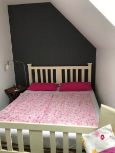 une chambre avec un lit blanc avec des draps roses dans l'établissement Ferienwohnung Landart, à Hilter