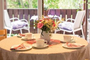 a table with plates and a vase with flowers on it at Gästehaus Elisabeth in Bad Staffelstein