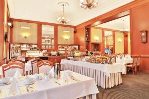 a dining room with white tables and chairs at Olympia Wellness Hotel in Karlovy Vary