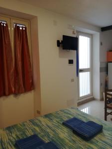 1 dormitorio con 1 cama, TV y ventana en Appartamento Osnao, en Cefalú