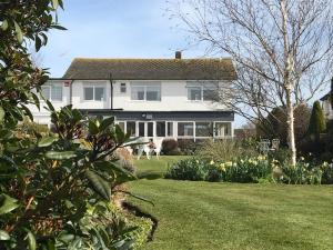 a white house with a yard with a dog at The Coast Yard B & B and Garden Chalets in Selsey