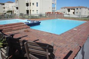 a swimming pool with a bench next to a building at Hermanus Beach Club in Hermanus