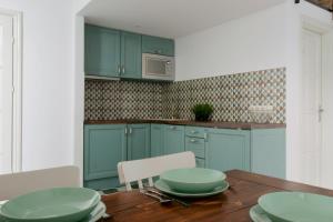 ブダペストにあるStandard Apartment by Hi5 - Wesselényi 8のキッチン(青いキャビネット、木製テーブル、皿付)