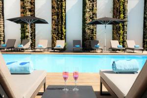 Iberostar Selection Lisboa في لشبونة: كأسين من النبيذ يجلسون على الطاولات أمام حمام السباحة