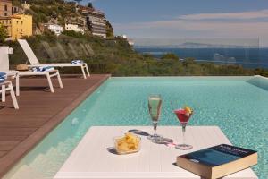 un tavolo con due bicchieri e un libro accanto alla piscina di Hotel Rivage a Sorrento