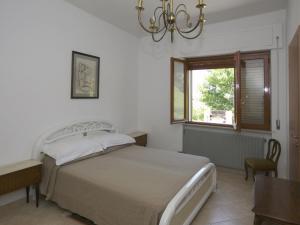 een slaapkamer met een bed, een raam en een kroonluchter bij Belvilla by OYO Casa grande in Corvara