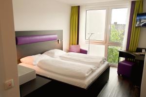 Un dormitorio con una cama grande y una ventana en B&F Hotel am Neumarkt, en Bad Hersfeld
