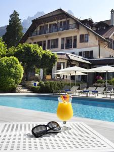 - une boisson et des lunettes de soleil assises sur une table à côté d'une piscine dans l'établissement Hotel Le Cottage Bise, à Talloires