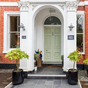 a green door on a house with two potted trees at Spot in the Woods in Lyndhurst