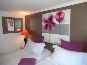 two beds in a hotel room with purple pillows at Hotel le P'tit Beaumont in Beaumont-en-Auge