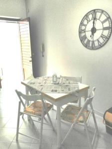 a table with two chairs and a clock on the wall at Il Mulino in San Vito lo Capo