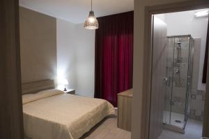 1 dormitorio con 1 cama y ducha acristalada en Barone Apartments, en Sciacca