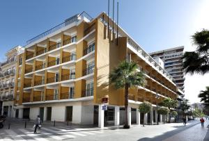 a yellow building with a palm tree in front of it at Exe Tartessos in Huelva