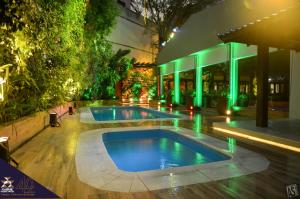a swimming pool in front of a building with green lights at Itaimbé Palace Hotel in Santa Maria