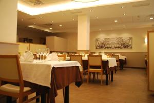 a dining room with tables and chairs and a painting at Aparthotel Meseguer in Alcañiz