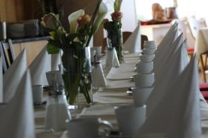 a long table with white plates and cups and flowers at Berg Gasthof Witthoh in Immendingen