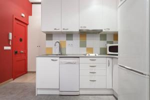 a kitchen with white cabinets and a red door at Nice apartment in Sants in Barcelona