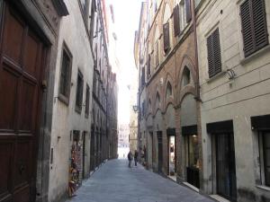 dos personas caminando por un callejón entre dos edificios en Real Taste of Siena, en Siena