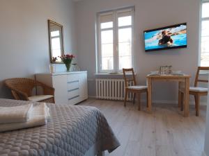 a bedroom with a bed and a table and a tv on the wall at Grand Tourist Gemini in Gdańsk