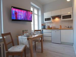 a kitchen with a table and a television on the wall at Grand Tourist Gemini in Gdańsk