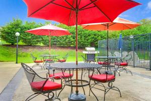 un patio con mesas y sillas y sombrillas rojas en Days Inn by Wyndham Towson, en Towson