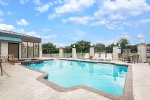 uma grande piscina com cadeiras e um pátio em Days Inn by Wyndham New Braunfels em New Braunfels