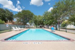 a swimming pool with lounge chairs and a fence at Days Inn by Wyndham Bryan College Station in College Station