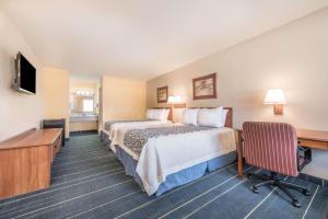 a hotel room with two beds and a desk at Days Inn by Wyndham Bryan College Station in College Station