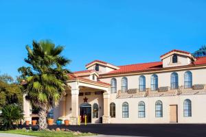 un gran edificio blanco con una palmera delante en Days Inn by Wyndham Seaworld Lackland AFB, en San Antonio