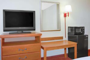 a room with a television on a dresser with a night stand with a night at Days Inn by Wyndham Mount Hope in Mount Hope