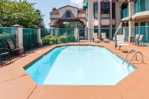a swimming pool on a patio with chairs and a house at Days Inn by Wyndham Franklin Nashville in Franklin