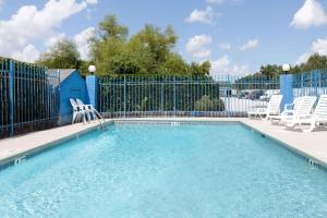 una piscina con sillas y una valla en Days Inn by Wyndham Columbia NE Fort Jackson en Columbia