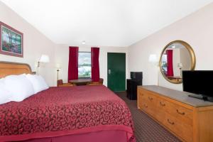 ein Hotelzimmer mit einem Bett und einem Spiegel in der Unterkunft Days Inn by Wyndham Columbia NE Fort Jackson in Columbia