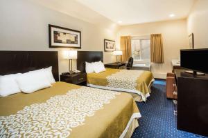 a hotel room with two beds and a flat screen tv at Days Inn by Wyndham Seattle Aurora in Shoreline