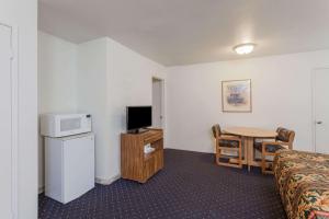 ein Hotelzimmer mit einem Bett und einem Tisch mit einer Mikrowelle in der Unterkunft Days Inn by Wyndham Anaheim West in Anaheim
