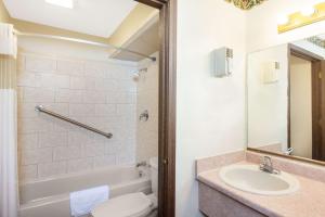 a bathroom with a sink and a toilet and a tub at Days Inn by Wyndham Erick in Erick