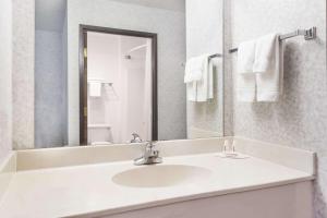 Baño blanco con lavabo y espejo en Days Inn by Wyndham Battlefield Rd/Hwy 65, en Springfield