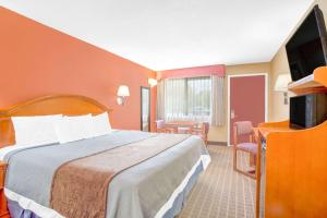 a hotel room with a bed and a flat screen tv at Days Inn by Wyndham Elko in Elko