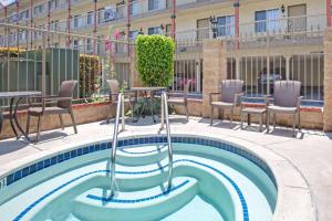 a swimming pool with chairs and tables in a building at Days Inn by Wyndham Los Angeles LAX/ Redondo&ManhattanBeach in Lawndale