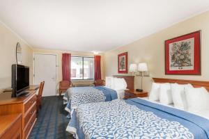 a hotel room with two beds and a flat screen tv at Days Inn by Wyndham Dover Downtown in Dover