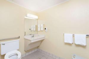 a bathroom with a sink and a toilet and a mirror at Days Inn by Wyndham Dover Downtown in Dover