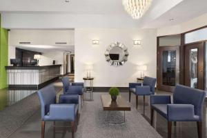 a lobby with blue chairs and a table and a mirror at Days Inn by Wyndham Montreal Airport Conference Centre in Dorval