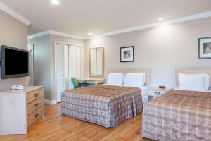 a hotel room with two beds and a flat screen tv at Days Inn by Wyndham San Francisco S/Oyster Point Airport in South San Francisco