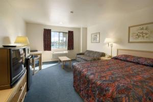 a hotel room with a bed and a flat screen tv at Days Inn by Wyndham Riverside Tyler Mall in Riverside