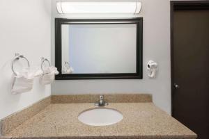 a bathroom with a sink with a mirror and a mirror at Days Inn by Wyndham Las Vegas in Las Vegas