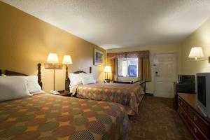 a hotel room with two beds and a flat screen tv at Days Inn by Wyndham Airport Nashville East in Nashville