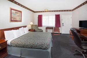 コスタメサにあるSunset Innのベッドとデスクが備わるホテルルームです。
