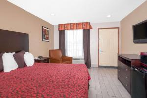 una camera d'albergo con letto rosso e TV di Days Inn by Wyndham Arcadia ad Arcadia